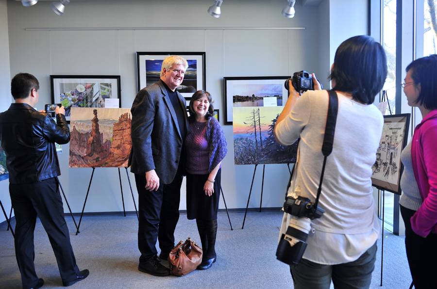 Local artist David Stickel (Left) takes pictures with his wife (Right) in front of Yan's paintings in the Global Education Center of the University of North Caroline at Chapel Hill. [Photo provided for China Plus by Yu Jie]