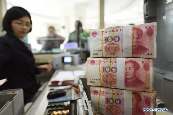 A bank staff member checks RMB banknotes at a bank in Lianyungang, east China's Jiangsu Province, Jan. 7, 2016. [Photo: Xinhua/Si Wei]