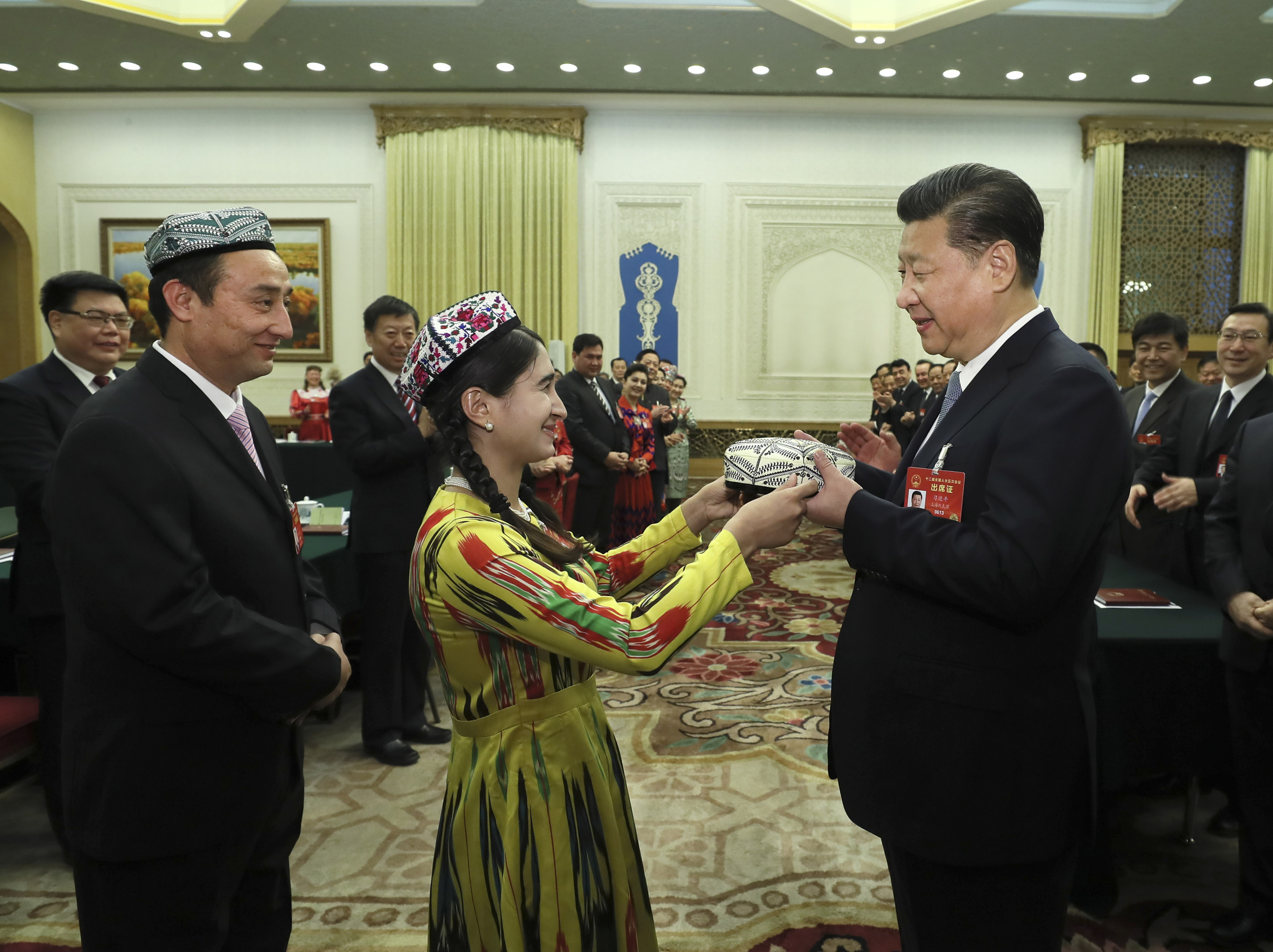 Chinese President Xi Jinping receives a gift from a national lawmaker from Xinjiang during a panel discussion at the ongoing annual session of the National People's Congress. [Photo: Xinhua/Lan Hongguang, Li Tao and Ma Zhancheng]