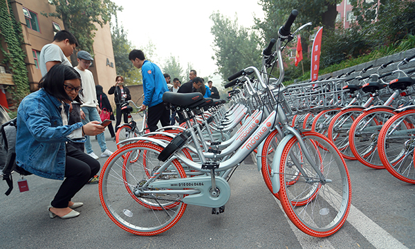 A citizen uses her cellphone to scan the QR code on a mobike in Beijing. [Photo: China Daily]