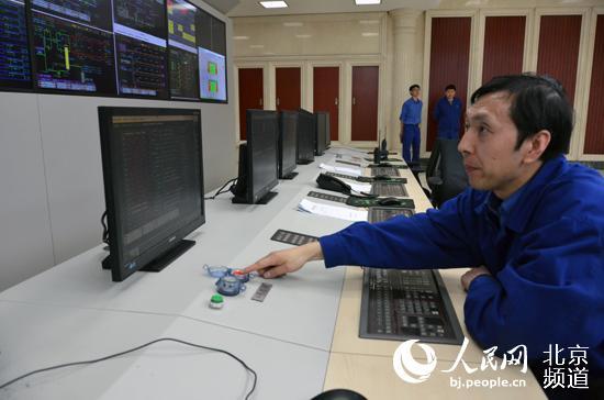Liu Yong, chief of the No 4 coal-fired unit, touches the button to suspend the unit on the morning of March 18, meaning the Huaneng Beijing Thermal Power Plant has suspended all operations. [Photo: People's Daily]