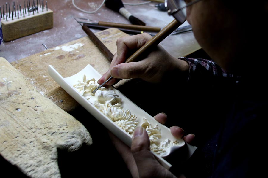 A craftsman working at the Beijing Ivory Carving Factory, March 31, 2017. China's State Council has announced that all ivory processing and trade in the country will be phased out by the end of 2017. [Photo: China Plus]