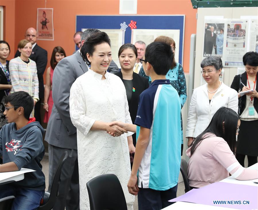 Peng Liyuan, wife of Chinese President Xi Jinping, talks with a student of Chinese descent in a class about politics and economics during her visit to the Bak Middle School of the Arts in West Palm Beach, Florida, the United States, April 7, 2017. Peng Liyuan, accompanied by U.S. First Lady Melania Trump (not pictured), visited the art school on Friday. [Photo: Xinhua/Wang Ye]