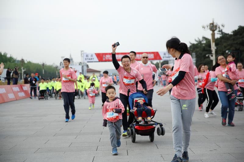 People attend a “family run” where participants ran a 420-meter course around the starting point of the Beijing International Running Festival on Sunday, April 16, 2017. [Photo: China Plus/Wang Lei]