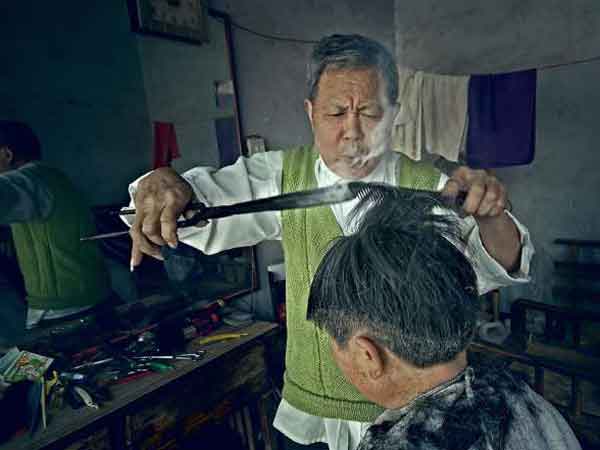 Old barber uses fire tongs to curl hair, evokes old times