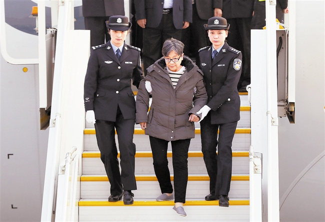 Yang Xiuzhu (C), No.1 of China's  100 most wanted fugitives red notice, is taking off the flight by police officers after she returned to China on Nov. 16, 2016. [File photo: baidu.com]