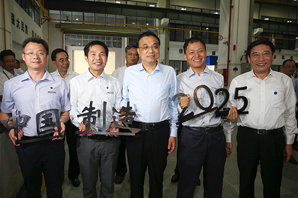Premier Li Keqiang takes photos with workers while holding the Chinese characters "Zhong Guo Zhi Zao," or made in China, at the Han's Laser Technology Industry Group Co Ltd in Dongguan, Guangdong province on Oct 13, 2016. [Photo: chinadaily.com.cn]
