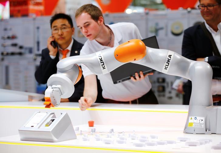 A Kuka technician programs a robot arm of German industrial robot maker Kuka at the company's stand during the Hannover Fair in Hanover, Germany, April 25, 2016. [Photo: Reuters]
