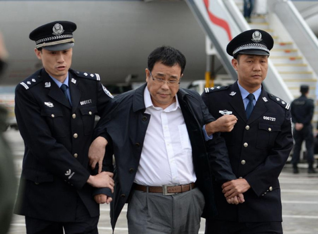 Chinese police escort Li Huabo (C), second of the list of China's "100 most wanted economic fugitives" after he arrived at Beijing Capital International Airport on May 9, 2015. [Photo: Xinhua]