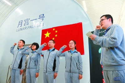 A group of volunteers taking an oath under the Chinese national flag before entering the simulated space capsule “Yuegong 1”, May 10, 2017. [Photo: Beijing Daily]