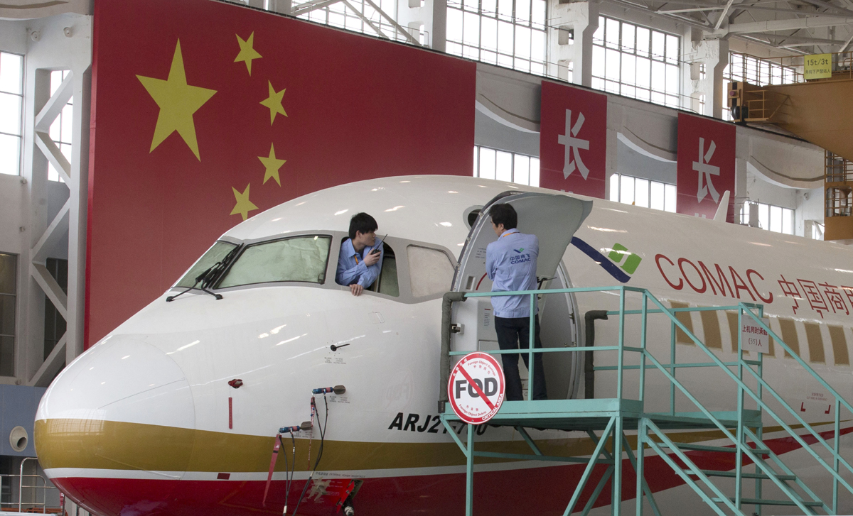 A worker peers out from the cockpit of an almost completed COMAC ARJ21-700 passenger jet at a final assembly and manufacturing center in Shanghai, May 21, 2014. [File Photo: AP/Ng Han Guan, Pool]
