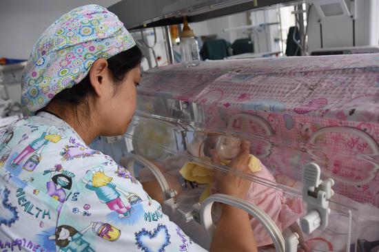 A nurse from Shaanxi Provincial No. 4 People's Hospital feeding breast milk from the human milk bank run by the hospital to an infant. [Photo: Xinhua]
