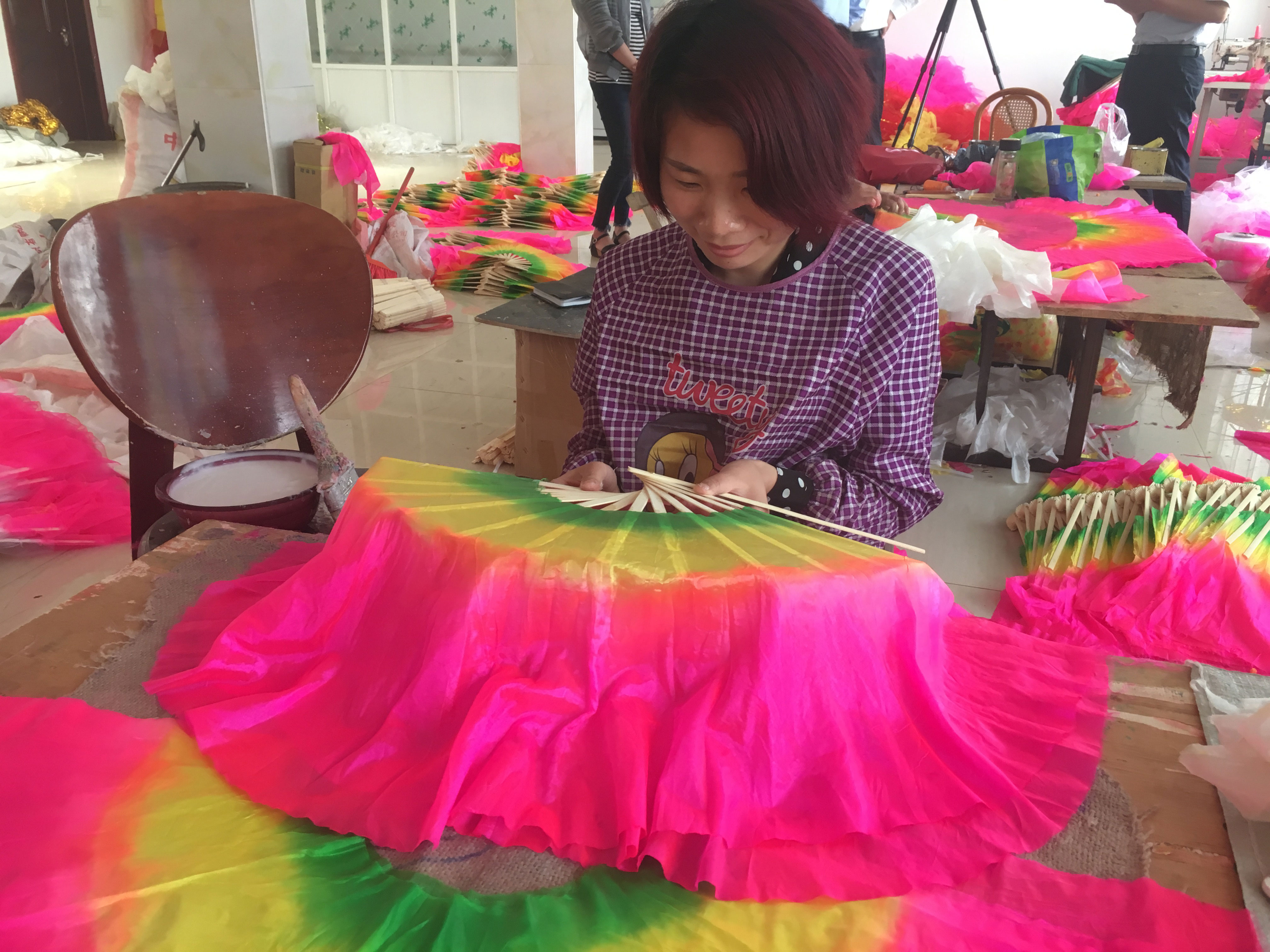 A female worker is working on a colorful fan to be sold via retail website Taobao.com [Photo: China Plus]