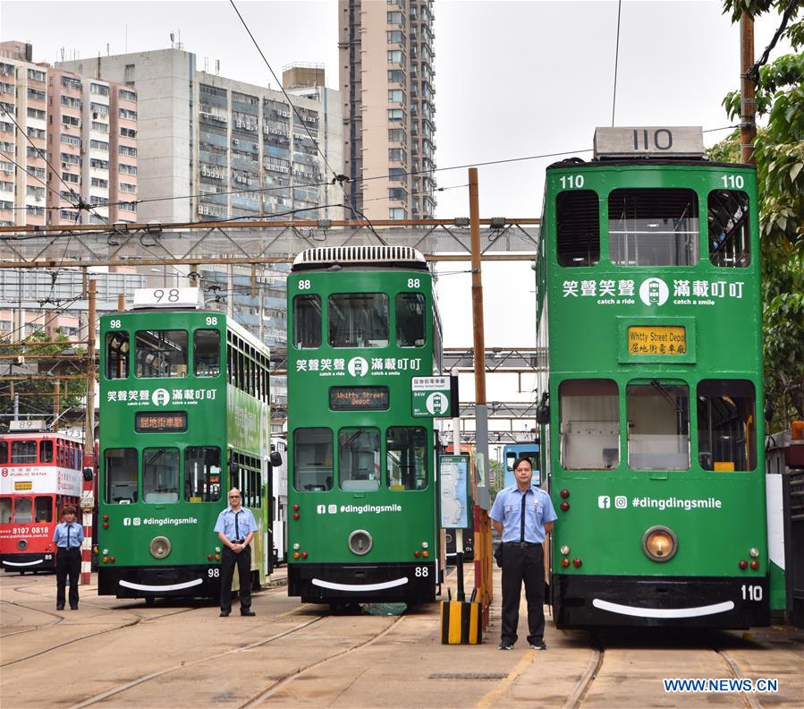 Staff members stand beside newly-decorated trams in Hong Kong, south China, May 26, 2017. The HK Tramways revealed its new logo on Friday. [Photo: Xinhua/Wang Xi]