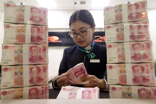 An employee at a bank counter counts renminbi. [Photo: Chinanews.com]
