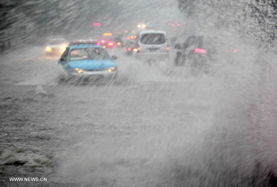 Motorcars try to run past a flooded road in Xuyi County of Huai'an City, east China's Jiangsu Province. A brief rainstorm hit the lower reaches of the Yangtze River on April 5, 2015. [Photo: Xinhua]