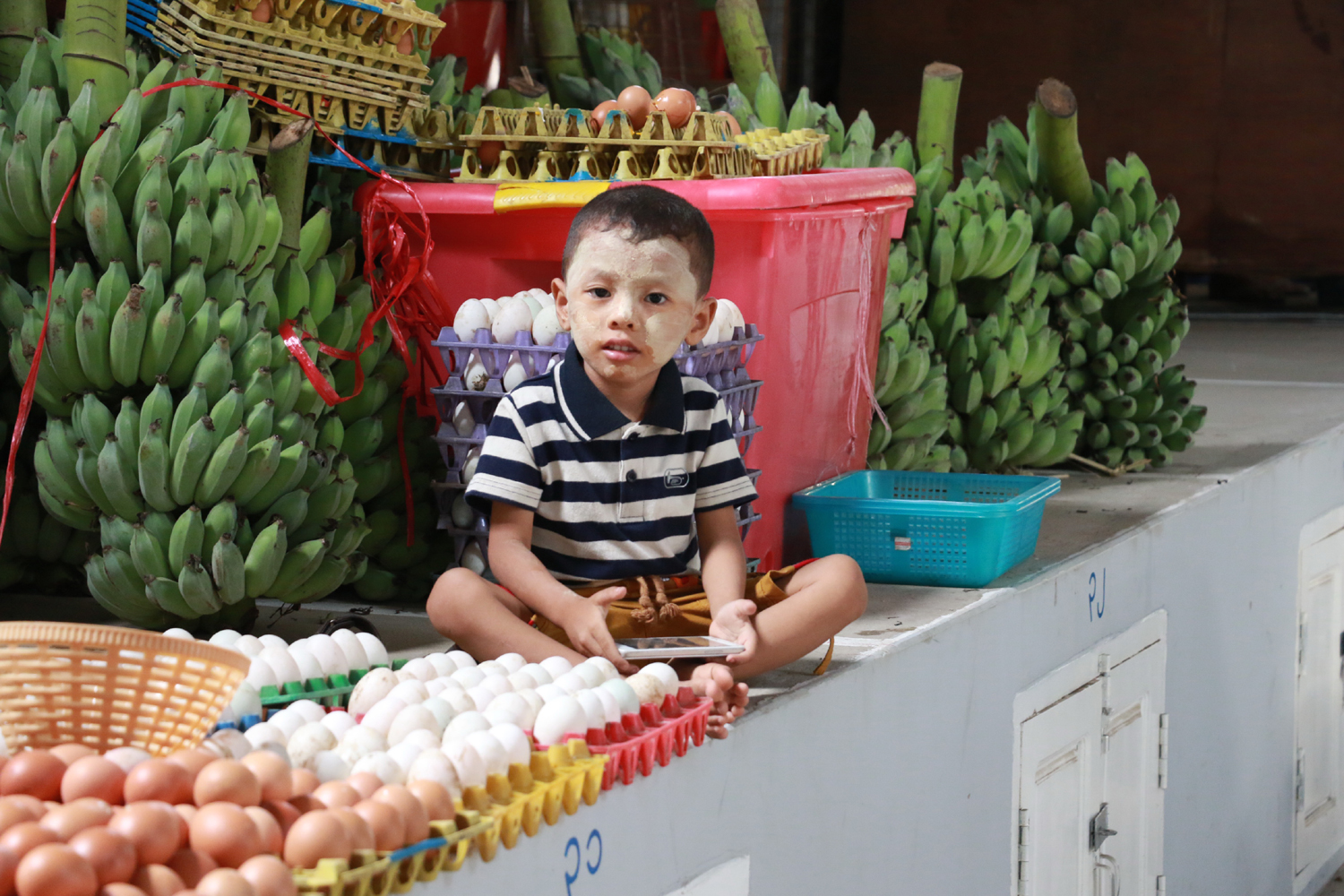 A boy sits on the commodity platform in the new market on May 27, 2017. [Photo: China Plus/Tu Yun]