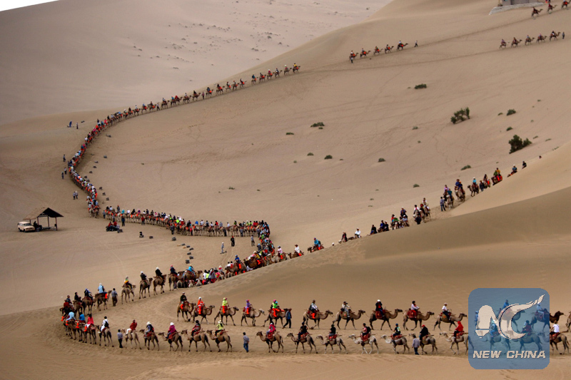 Tourists ride camels at the crescent spring of the Mingsha Hill in Dunhuang, northwest China's Gansu Province. Dunhuang was a key trading post situated on the ancient "Silk Road". [File Photo: Xinhua]