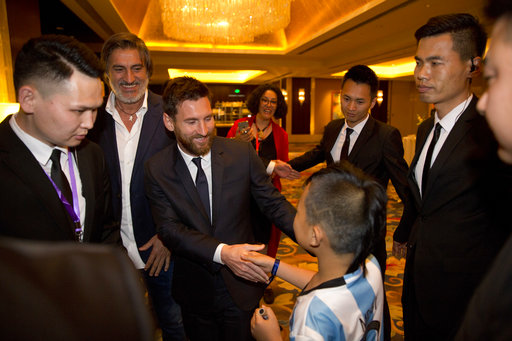 Barcelona's Lionel Messi, centre, shakes hands with a young fan as he arrives for an event to launch the establishment of Messi Experience Park in Beijing, China, Thursday, June 1, 2017. [Photo: AP/Ng Han Guan]