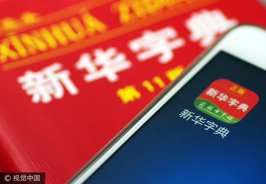 A mobile phone installed with the official app of Xinhua Dictionary on a paper edition of the dictionary [Photo: VCG]