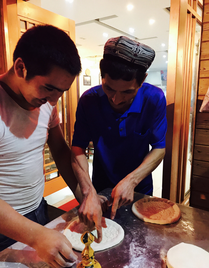 Abdulla is working together with one of his employee in his own restaurant. [Photo: China Plus]