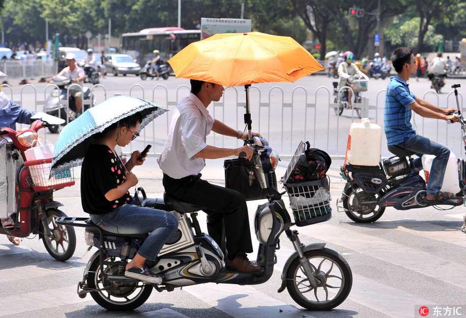 A motorcyclist rides with a sunshade on a hot day in Fuzhou, Fujian province. [File Photo: IC]