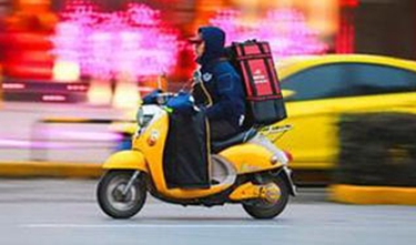 Photo shows a food delivery staff is on his way to deliver food. [File photo: Xinhua]