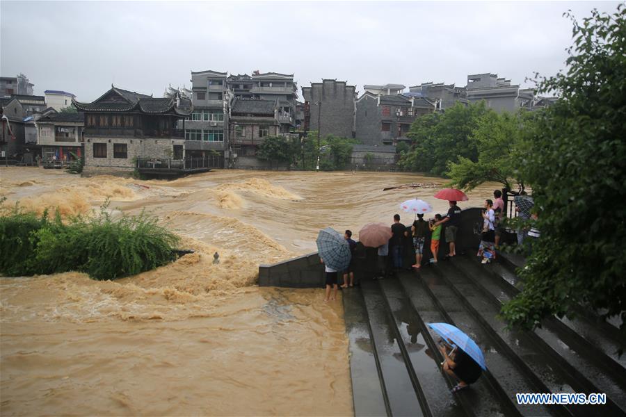 People look at flood at the riverside of Wanrong River in Jishou City, central China's Hunan Province, June 23, 2017. Heavy rain has hit Xiangxi Tujia and Miao Autonomous Prefecture of Hunan since Thursday. [Photo: Xinhua/Peng Biao]