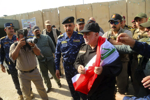 Iraq's Prime Minister Haider al-Abadi, center, holds a national flag upon his arrival to Mosul, Iraq, Sunday, July 9, 2017. Backed by the U.S.-led coalition, Iraq launched the operation to retake Mosul from Islamic State militants in October. [Photo: Iraqi Federal Police Press Office via AP]