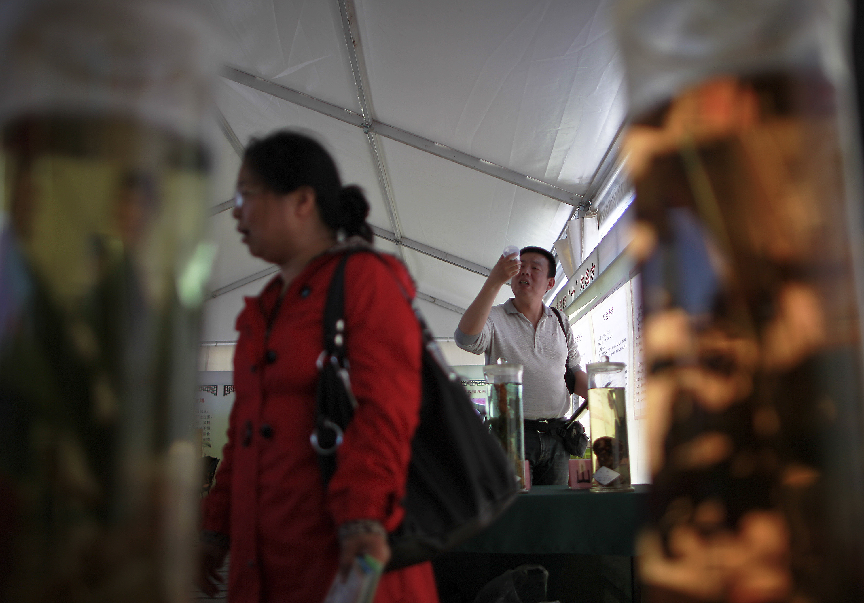 A Chinese man takes a closer look at a Chinese medicine on display at a booth during a Health Culture Festival held at the Ditan Park in Beijing, China Friday, May 13, 2011. [Photo: AP]