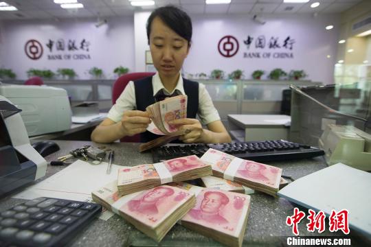 Bank employee counts 100 RMB notes at a Bank of China branch in Taiyuan, capital of Shanxi Province. [Photo: Chinanews.com]