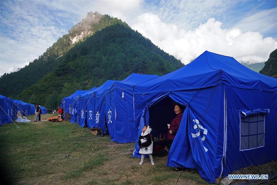 A woman takes a child out of a tent at a temporary shelter in Zhangzha Village of Zhangzha Town in Jiuzhaigou County, southwest China's Sichuan Province, Aug. 11, 2017. Temporary shelters were established in Jiuzhaigou after a 7.0-magnitude earthquake struck Jiuzhaigou County on Tuesday. Quake-affected people received relief supplies and started their lives in tents. [Photo: Xinhua]