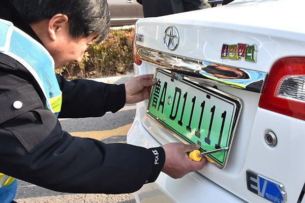 An employee of the Jinan vehicle administration department installs a plate on an electric car in Jinan, Shandong province, on Dec 1, 2016.[Photo: China Daily/ by Xu Suhui]