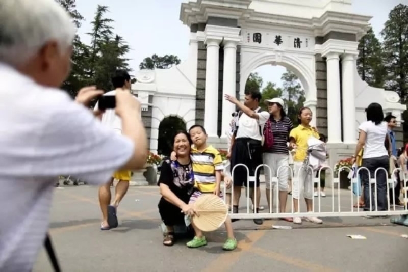 Tourists pose for photos in front of the gate of Tsinghua University. [Photo: China Youth Daily]