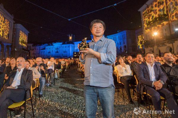 Chinese director Wang Bing holds a trophy at the Locarno film festival in Switzerland. [Photo: Artron.net]