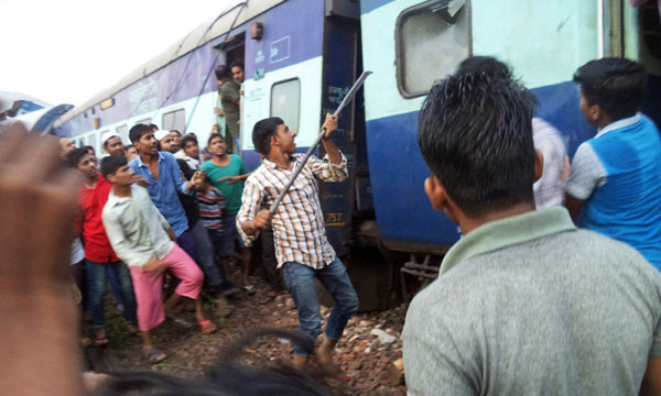 A volunteer breaks the glass of a train compartment window to rescue passengers trapped after an accident near Khatauli, in the northern Indian state of Uttar Pradesh, on August 19, 2017. [Photo: Imagine China]